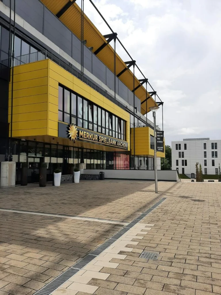 Eingang der MERKUR SPIELBANK Aachen mit gelber Fassade