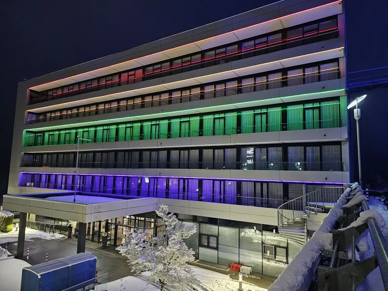 Nachtaufnahme des Ring Casino Gebaeudes beleuchtet mit farbigen LED Lichtbaendern und Schnee auf dem Boden