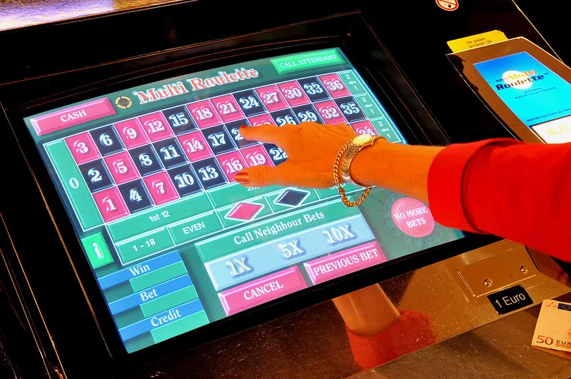 Eine Hand tippt auf den Bildschirm eines elektronischen Multi Roulette Terminals im Ring Casino